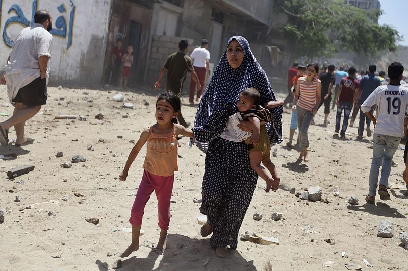 Una mujer huye con sus hijos de uno de los bombardeos sobre Gaza