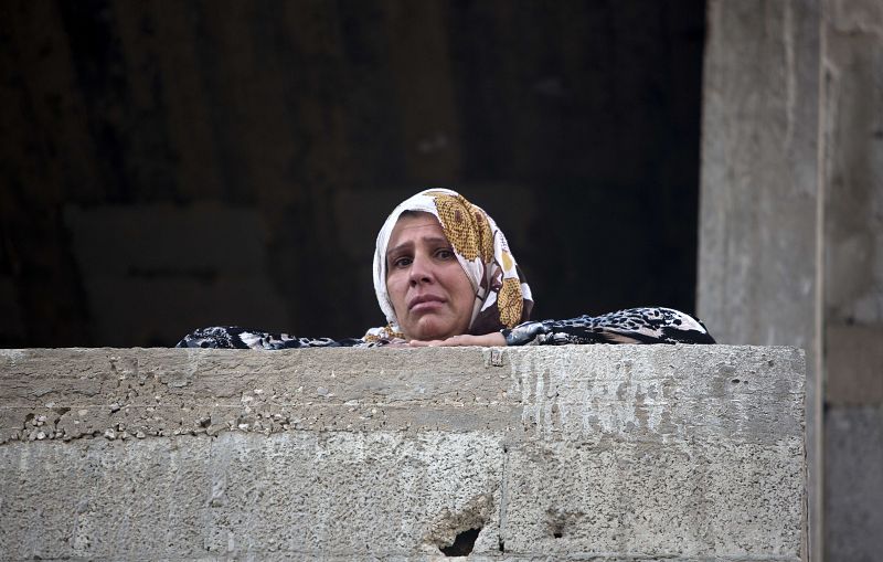 Una mujer palestina observa los restos de un coche destruido por un ataque aéreo israelí