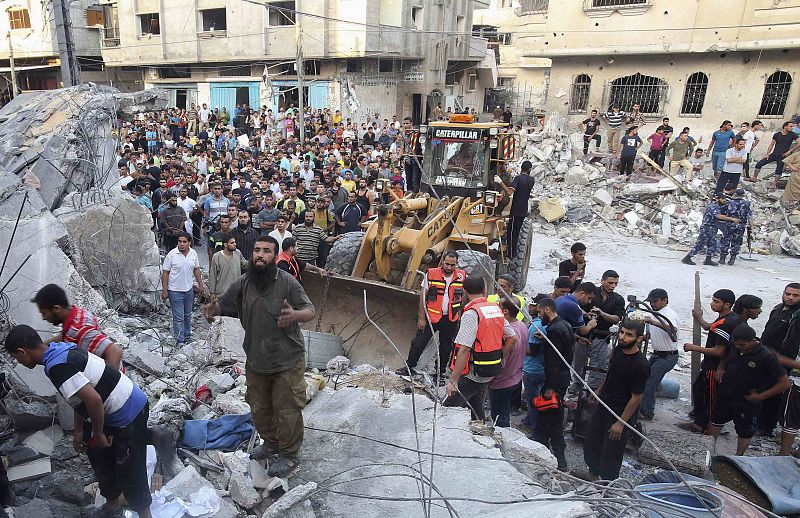 Un grupo de palestinos y equipos de rescate buscan víctimas en las ruinas de una casa destruida tras el ataque aéreo israelí sobre la ciudad de Rafah, al sur de la Franja de Gaza