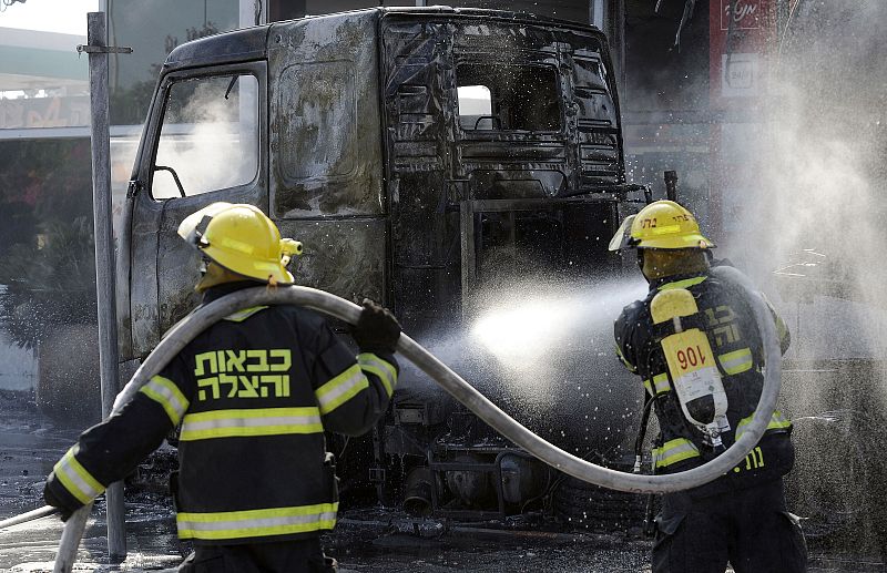 Bomberos israelíes extinguen el fuego de un vehículo destrozado por un cohete lanzado desde Gaza, que impactó en una gasolinera en la ciudad de Ashdod.  