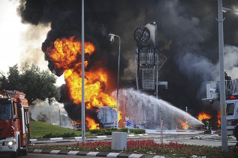 Bomberos israelíes extinguen las llamas provocadas por el impacto de un cohete en una gasolinera en Ashdod (Israel)