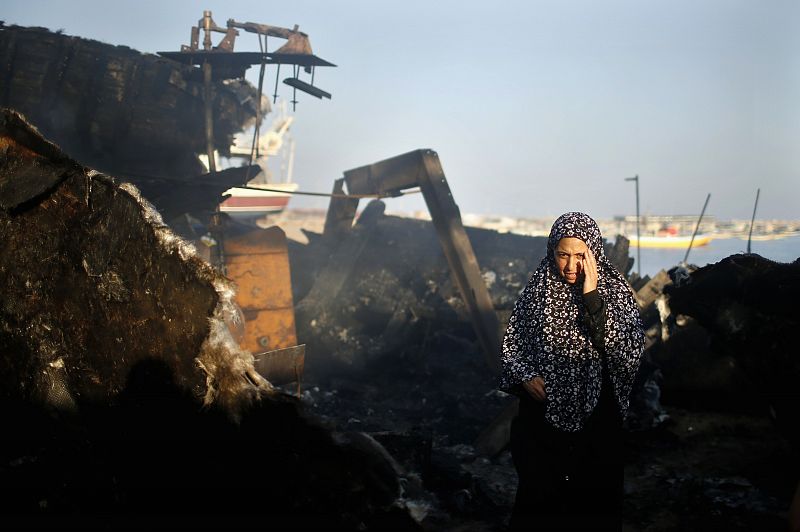 Una mujer palestina se lamenta tras ver los restos del barco de su hijo, dañado en uno de los ataques israelíes, en el puerto de Gaza