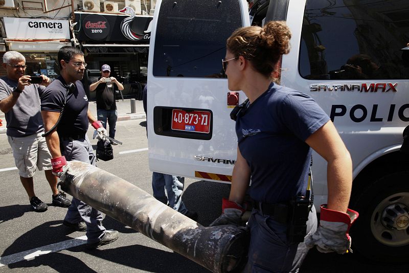 Expertos en bombas de la policia israelí retiran parte de un cohete lanzado desde Gaza hacia la costa mediterránea de la ciudad de Tel Aviv