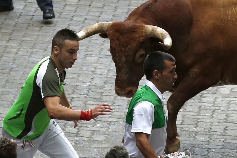 Uno de los toros de Miura se dirige hacia dos corredores