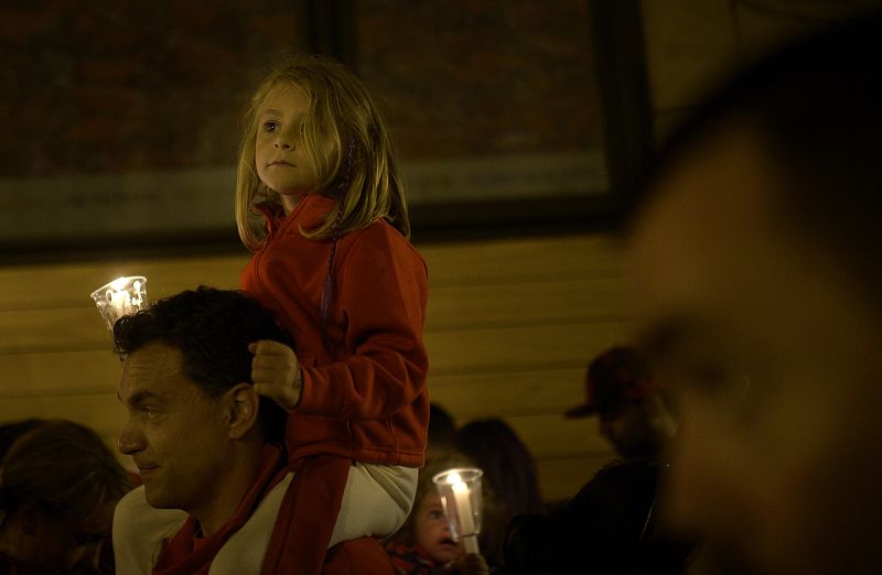 Una niña sostiene una vela a hombros de su padre en el evento que cierra las fiestas de San Fermín en Pamplona.
