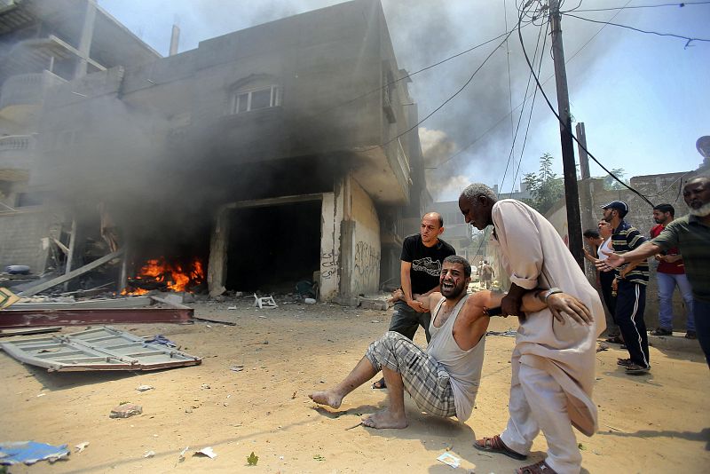 Dos palestinos evacúan a un hombre herido en la jornada más sangrienta en Gaza.