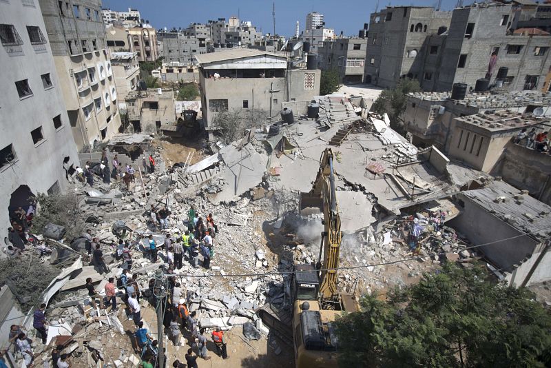 Palestinos buscan supervivientes entre las ruinas de un edificio derribado por misiles israelies.