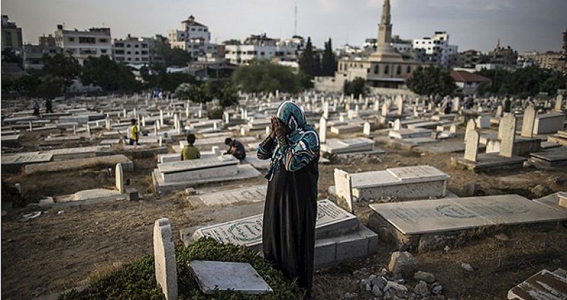 Una mujer palestina reza sobre la tumba de un familiar en el cementerio al noroeste de la ciudad