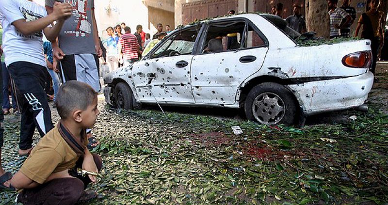 Un niño palestino mira un coche dañado por una explosión en un jardín público en la ciudad de Gaza