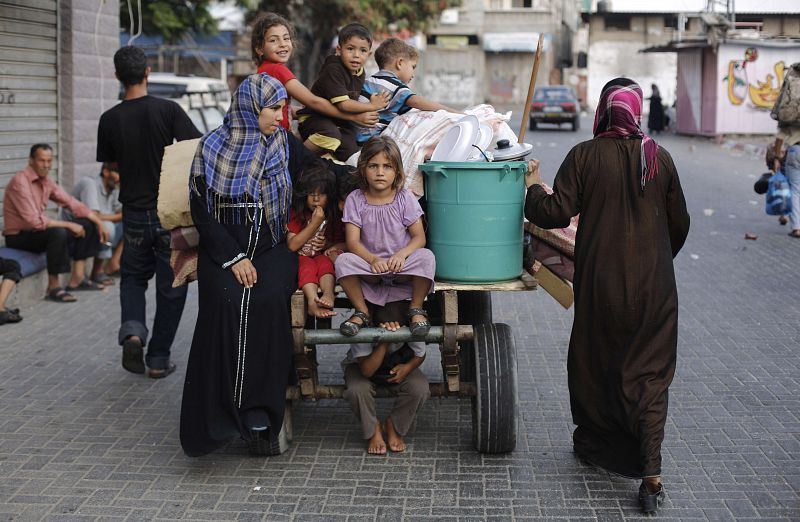 Mujeres y niños palestinos cargan sus enseres en un carro para volver a sus hogares durante la tregua pactada entre Israel y Hamás