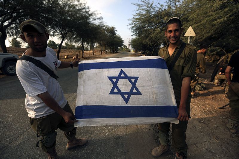 Dos soldados israelíes muestran una bandera israelí tras retirarse de la Franja de Gaza a las 8 de la mañana