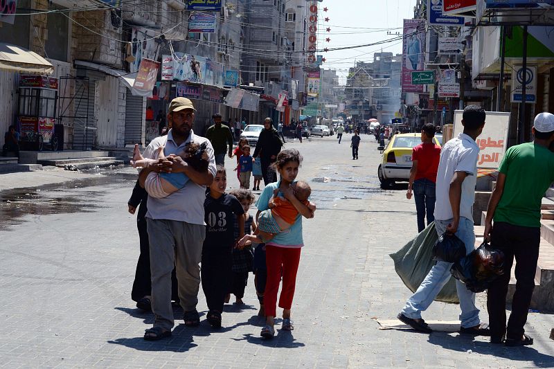 Un palestino, con su hijo menor en brazos, y su familia se dirigen a una escuela de la ONU en busca de refugio tras la reanudación de los ataques en el barrio gazatí de Jabalia