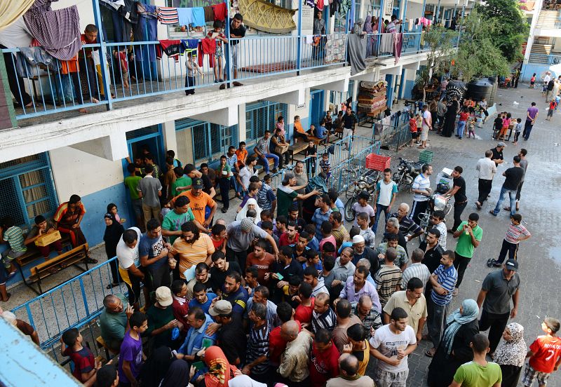 Una multitud de palestinos refugiados en una escuela de la ONU se agolpa ante un oficial para recibir comida