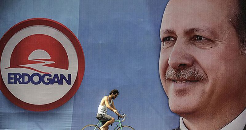 Un hombre monta una bicicleta junto a un cartel de la campaña del primer ministro turco, Recep Tayyip Erdogan