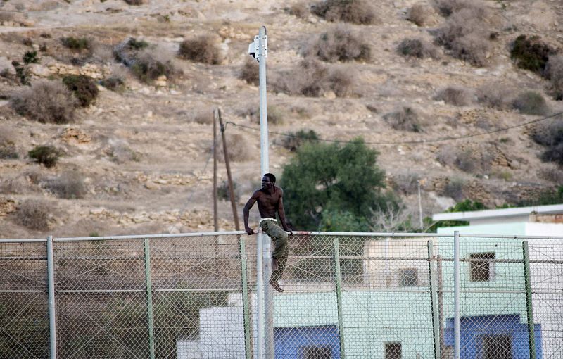 Un inmigrante subsahariano intenta mantenerse encaramado a la valla de Melilla