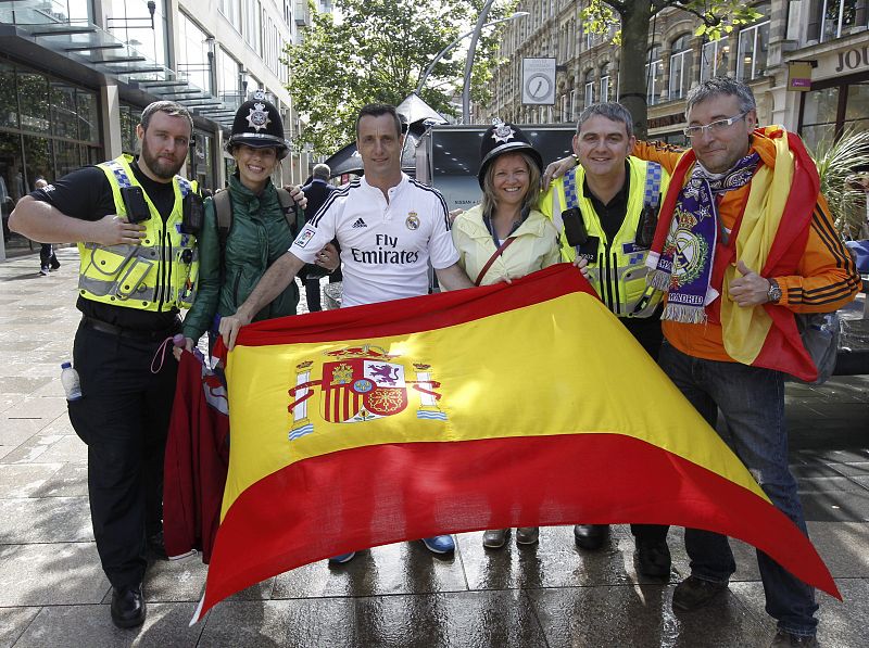 Aficionados madridistas posan junto a dos agentes de Policíaen las calles de Cardiff (Gales), horas antes del comienzo del la final de la Supercopa de Europa.