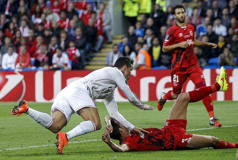 El portugués del Real Madrid Cristiano Ronaldo (i) cae junto al defensa Fernando Navarro, del Sevilla CF.