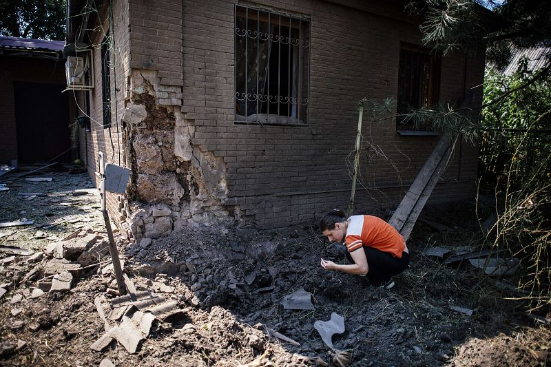 Una mujer recoge metralla después de que proyectiles de artillería pesada cayesen en el centro de Donetsk