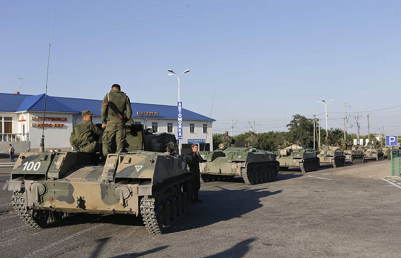 Russian military personnel sit atop armoured vehicles outside Kamensk-Shakhtinsky