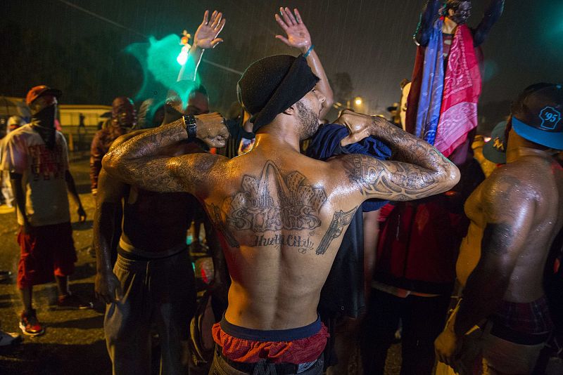 Protesters gesture as they stand in a street in defiance of a midnight curfew in Ferguson