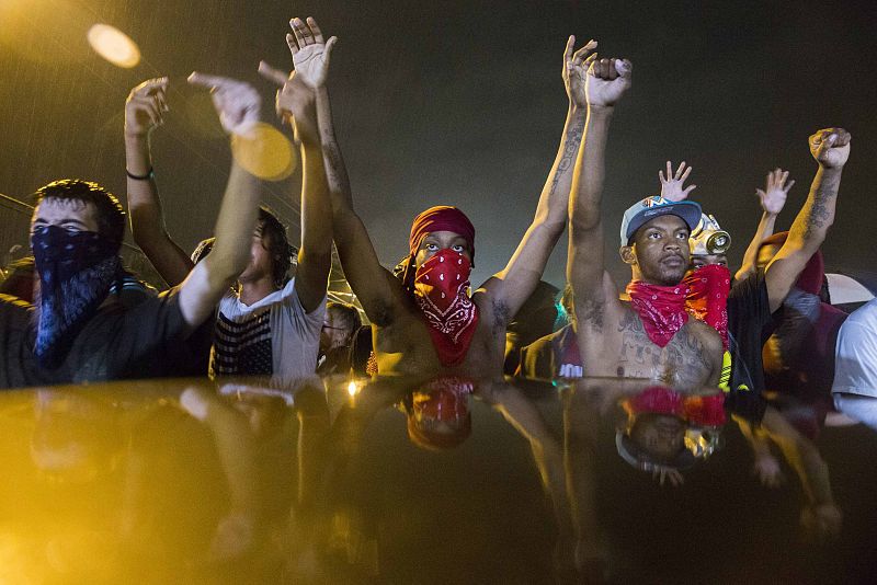 Protesters gesture as they stand in the street in defiance of a midnight curfew in Ferguson, Missouri