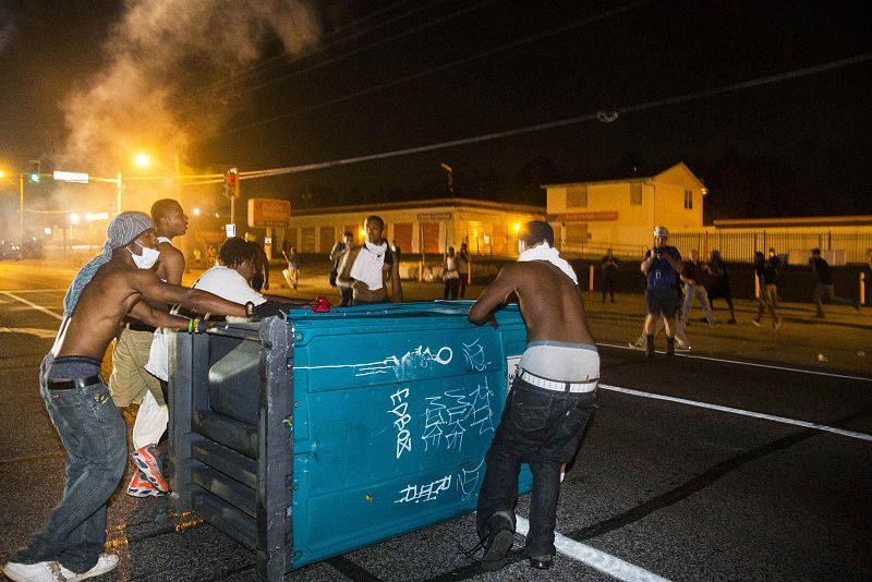 Jóvenes manifestantes arrastran un baño portátil a la carretera durante las protestas tras la muerte de Michael Brown por disparos de un policía