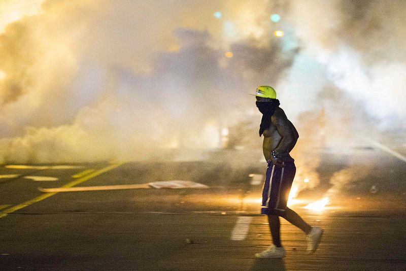 Un manifestante atraviesa una nube de gas lacrimógeno lanzado por las autoridades