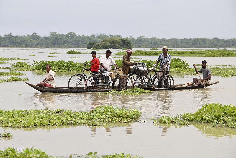 Un grupo de indios transportan sus bicicletas en una barca por las zonas afectadas por la inundación al noroeste de la India