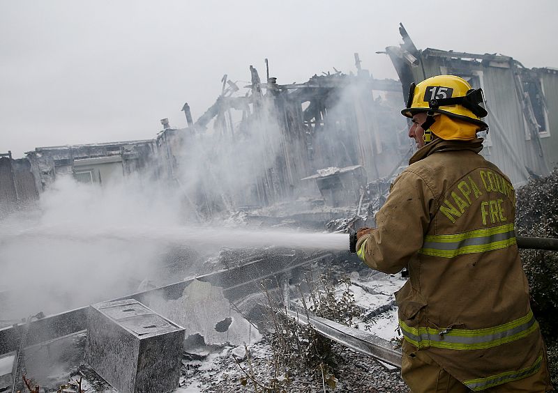 Un bombero apaga el fuego de varias casas tras un terremoto en el norte de California.