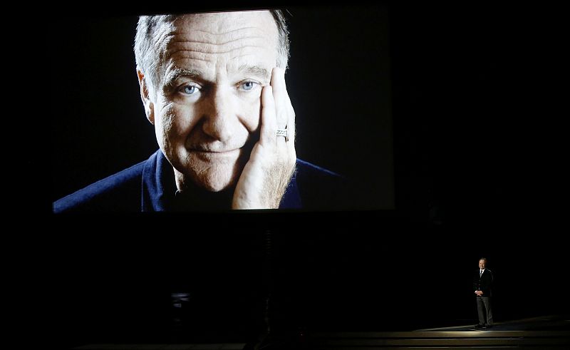 Billy Crystal takes the stage to pay tribute to Robin Williams, shown on a large screen, during the 66th Primetime Emmy Awards in Los Angeles