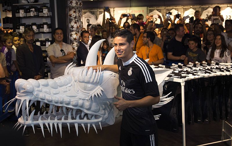 El centrocampista colombiano James Rodríguez posa junto a una figura del dragón que aparece en el torso de la nueva camiseta del Real Madrid.