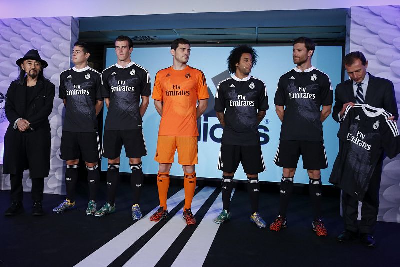 El diseñador Yohji Yamamoto (i) posa junto a los jugadores del Real Madrid James Rodríguez, Garet Bale, el portero Iker Casillas, Marcelo y Xavi Alonso y el director de Relaciones Institucionales del club, Emilio Butragueño (i-d), en la presentación