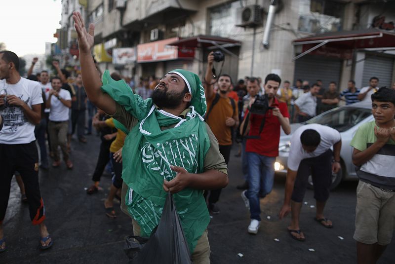 A Palestinian throws sweets as others celebrate what they said was a victory over Israel, following a ceasefire in Gaza City