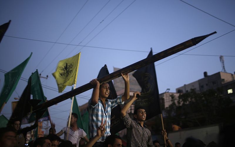 A Palestinian carries a mock rocket as he celebrates with others what they said was a victory over Israel, following a ceasefire in Gaza City