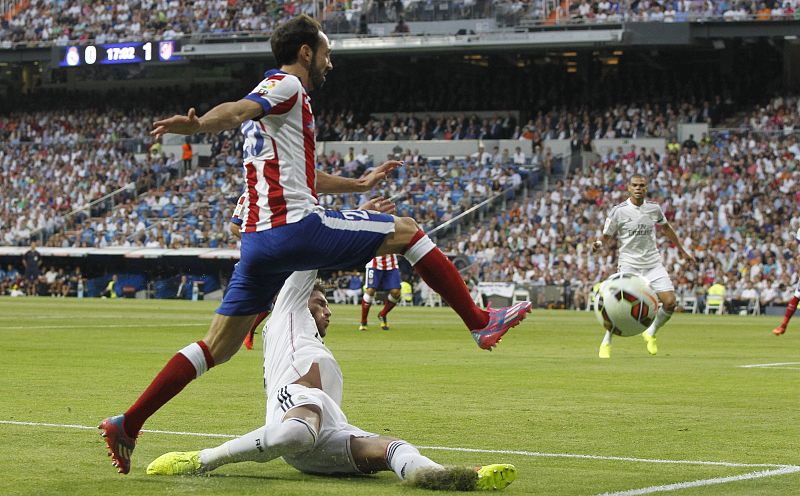 El defensa del Atlético de Madrid Juanfran (arriba) lucha un balón con Sergio Ramos, del Real Madrid.