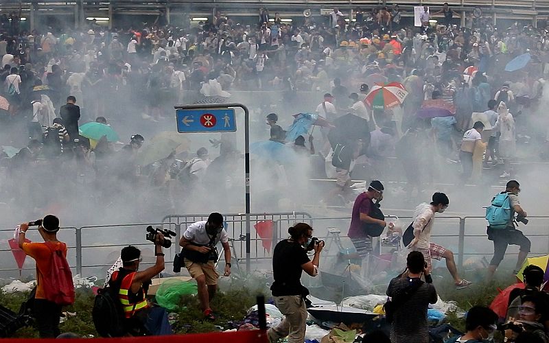 Varias personas corren después de que la policía lanzara gases lacrimógenos en Hong Kong.