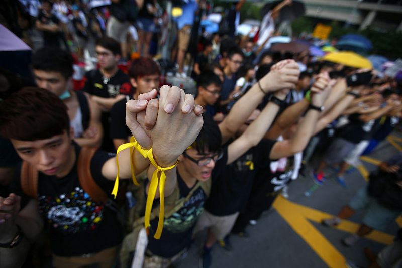 Los manifestantes se dan la mano en la plaza Baihinia. Lucen lazos amarillos, uno de los emblemas del movimiento pro-democracia