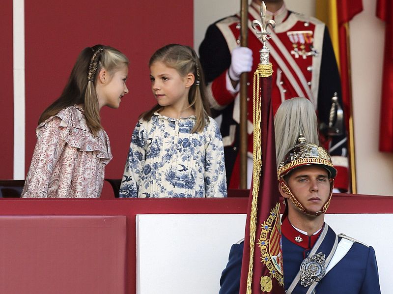 La princesa Leonor y la infanta Sofía, conversan en la tribuna instalada en la plaza de Neptuno de Madrid, durante el desfile militar.