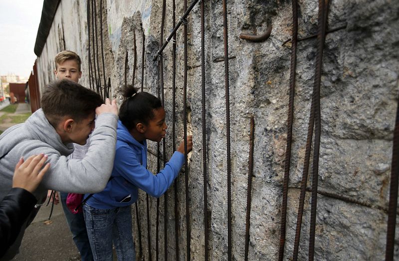 Varios niños miran a través de un agujero de la antigua frontera del Muro de Berlín en la Bernauer Strasse, en Berlín.