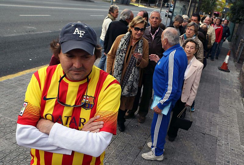 Un ciudadano con la camiseta del FC Barcelona formando cola en la Vía Augusta de Barcelona.