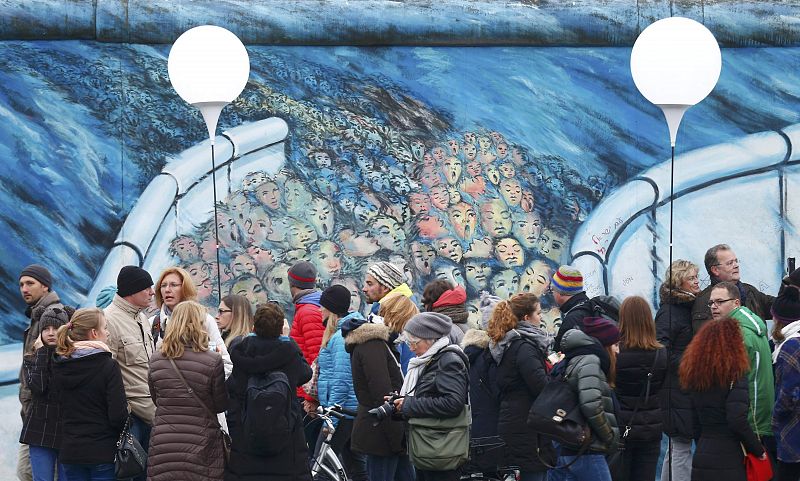 Varias personas junto a un pedazo del muro de Berlín 25 años despues de su caída