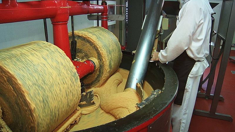 Para hacer el turrón de Jijona la masa se estampa en bandejas para que se enfríe, se pasa por este molino de piedra que tritura las almendras y por esta batidora gigante hasta que quede un producto mucho más líquido.