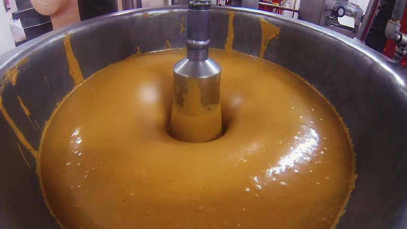 Para hacer el turrón de Jijona la masa se estampa en bandejas para que se enfríe, se pasa por este molino de piedra que tritura las almendras y por esta batidora gigante hasta que quede un producto mucho más líquido.