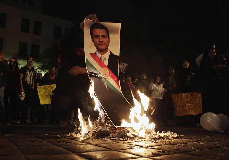 Un manifestante prende fuego a una fotografía del presidente de México, Enrique Peña Nieto, durante las protestas por la desaparición de los 43 estudiantes