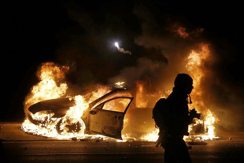 Un coche de policía arde en Ferguson tras la decisión del jurado de no imputar al policía que habría matado al joven Michael Brown el pasado agosto.