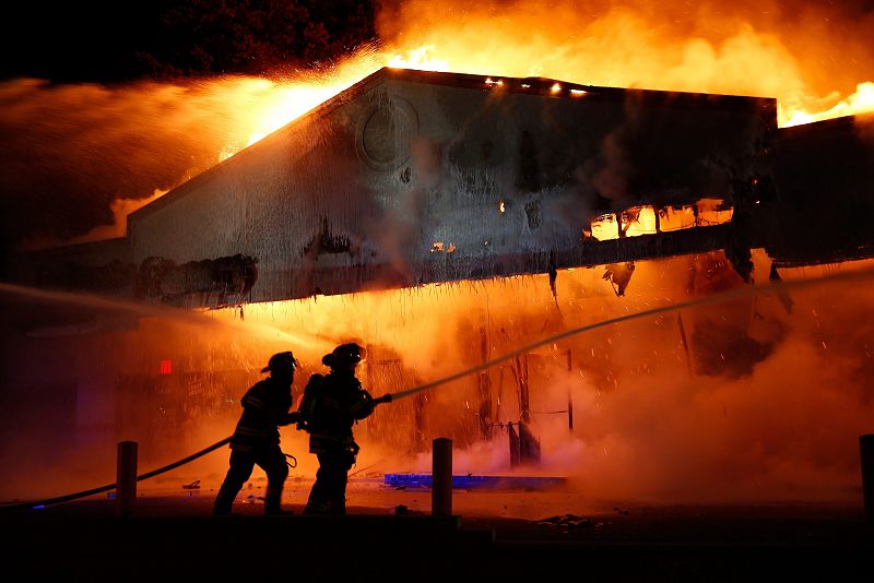 Unos bomberos intentan apagar el fuego en un establecimiento comercial luego de que resultara afectado durante las protestas en Ferguson.