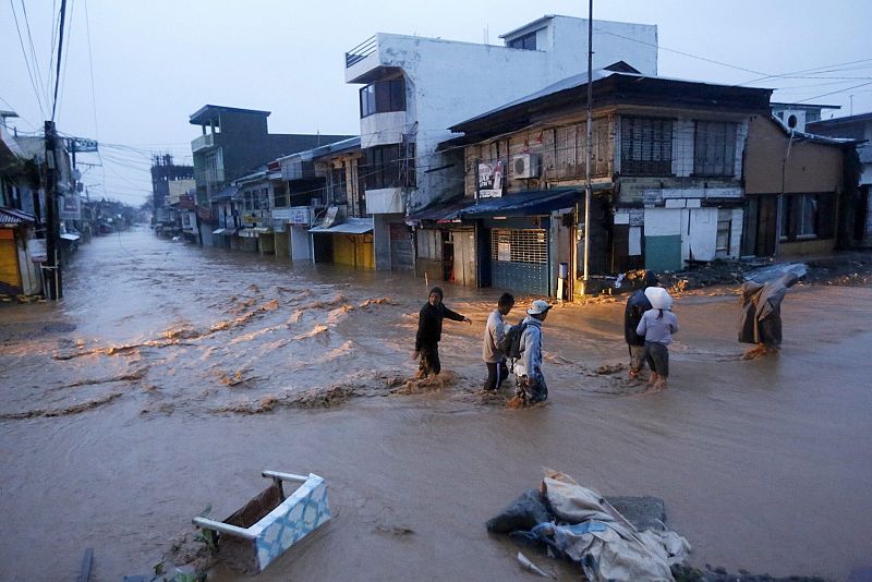 Un grupo de vecinos camina por una calle inundada tras el paso del tifón Hagupit por filipinas.