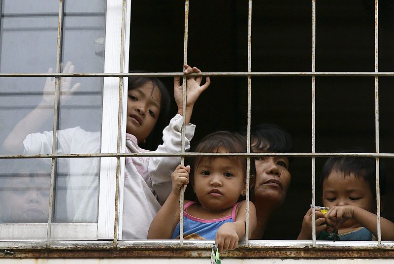 Una familia mira desde la ventana de un colegio convertido en refugio en un suburbio de Manila