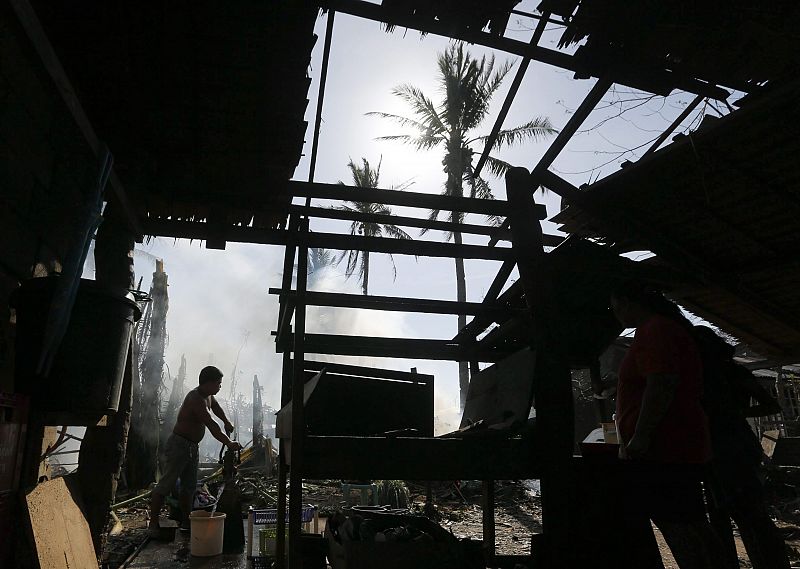 Un hombre coge agua en una fuente en medio de los destrozos causados por el tifón en Dolores, en la isla de Samar