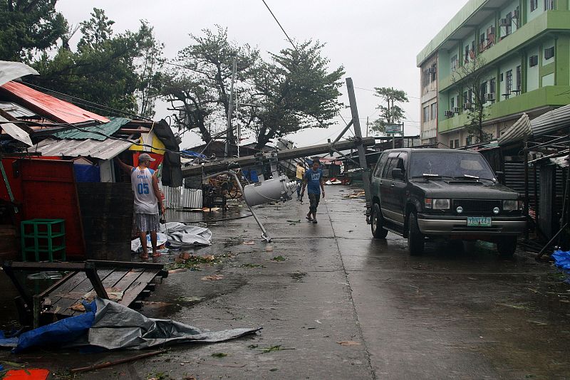 Un hombre camina por una calle con los postes eléctricos derribados en Tacloban